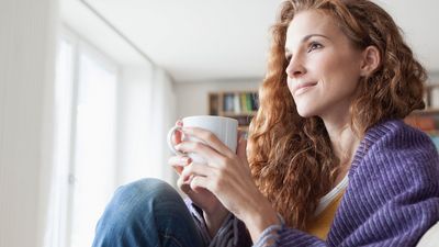 Person enjoying a warm beverage in a cozy setting, dressed in a soft sweater.