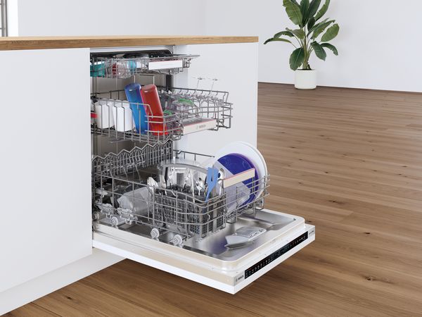 Open vaatwasser met schone gerechten en keukengerei binnen, geplaatst in een moderne keuken.