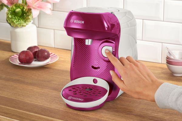 A person clicks on the start button of TASSIMO HAPPY coffee machine.
