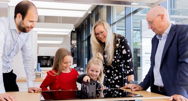 Familie verzameld rond een computer, bespreken of samenwerken.