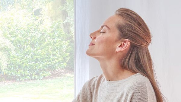 A woman with her eyes closed inhales deeply and pleasurably.