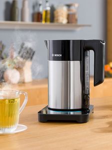 Kettle and hot mug of herbal tea on countertop