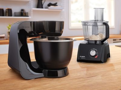 Robot multifonctions Bosch et robot culinaire Bosch sur un plan de travail en bois à côté d'un gâteau.