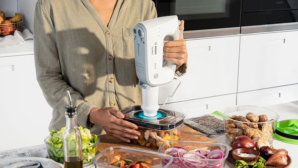 Une personne met sous vide une boîte de conservation à l'aide d'un batteur Bosch.