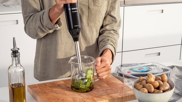 Une personne se tenant près d'un plan de travail mixe des aliments à l'aide d'un mixeur plongeant Bosch.
