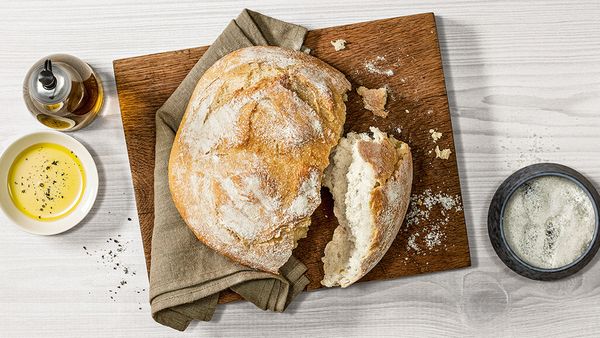 Un pain blanc croustillant fraîchement cuit sur une planche à découper en bois.