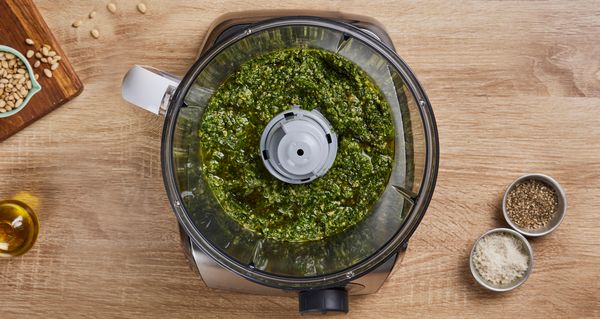 Vue aérienne de la préparation d'un pesto dans un robot culinaire.