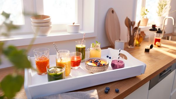 Différents smoothies posés sur un plan de travail dans la cuisine.