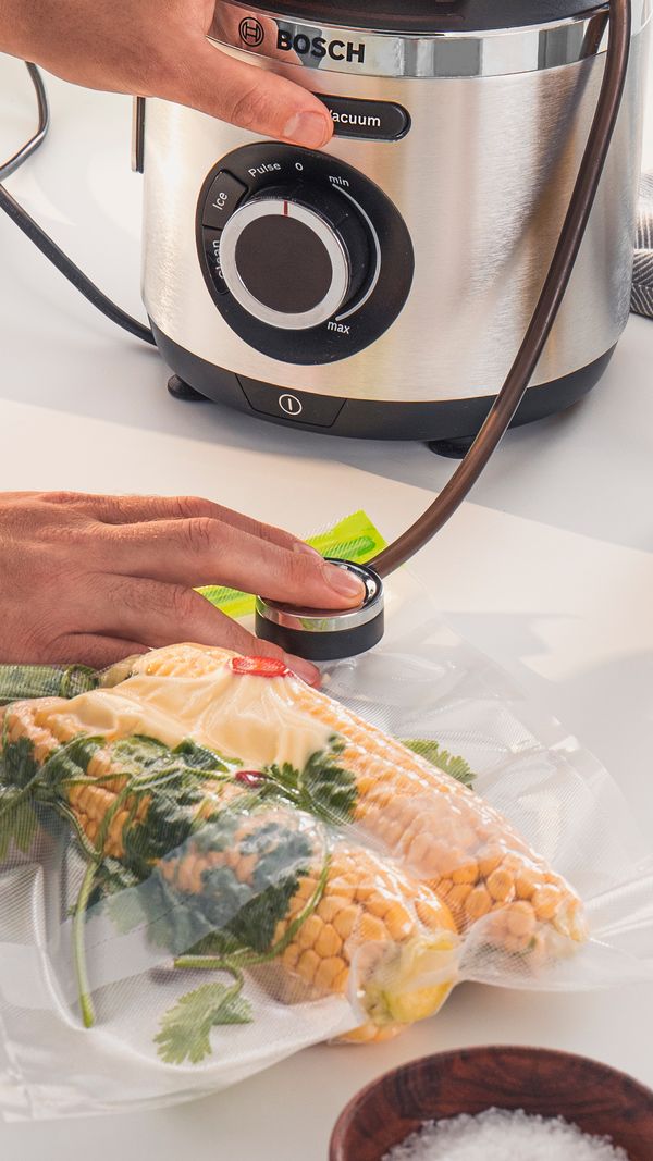 Une personne appuie sur un bouton pour aspirer l'air et conditionner sous vide les aliments.