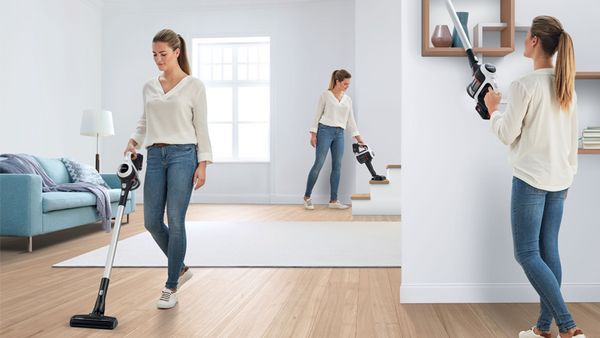 Woman with cordless vacuum cleaner deep cleaning house