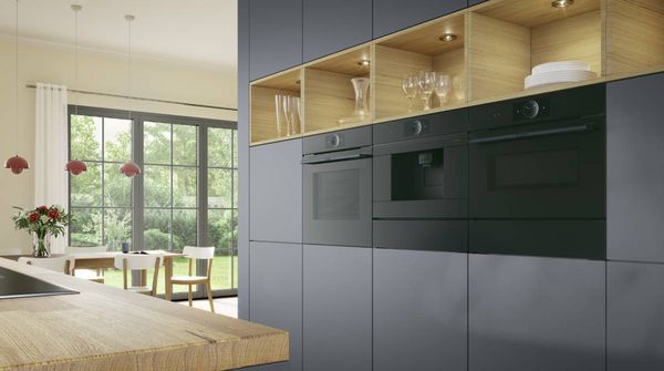 Een keuken voor de fervente kok: een ingebouwde inductiekookplaat op een modern kookeiland met broccoli in een pan en twee ovens op borsthoogte op de achtergrond