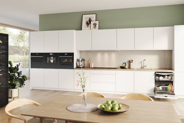 Eenvoudige rechte keuken met lichtbruine elzenhouten kasten en een witte eetkamerset